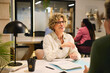 © Rido - Mature businesswoman working with colleagues at desk in creative office