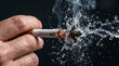 © startang141 - A hand holding a burning cigarette being extinguished by a splash of water, creating smoke and droplets.