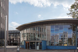 An eye-level architectural photograph of the Tränenpalast, a historical border crossing building located near Friedrichstraße station in Berlin, Germany, featuring a modern glass facade, blue tiled. 