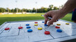 © RRStock - Coach analyzes strategy on soccer field board