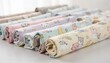 © DigitalSpace - Display of assorted childrens pajama fabric rolls in pastel cartoons and calm neutrals showing smooth interlock knit ideal for durable breathable nightwear collections.
