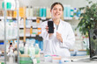 © JackF - Woman pharmacist holds a mobile phone in her hands and offers to use an online application for ordering and paying in a pharmacy
