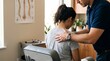 © AlfaSmart - Chiropractor adjusting back of woman sitting on treatment chair. Osteopath examining patient for spinal alignment and pain relief. Professional physical therapy clinic session concept.