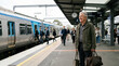 © Xenia - Smiling senior man waiting on a train station platform with luggage. Active elderly male passenger traveling by public transportation