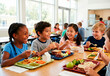 © Xenia - Diverse group of elementary school children eating lunch together in a bright cafeteria. Happy kids enjoying healthy meals and talking at a table