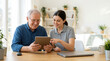 © Xenia - Young woman helping an elderly man with a tablet. Happy senior caucasian grandfather and granddaughter using technology together at home