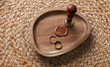© splitov27 - Gold rings and vintage sealing wax stamp in a wooden tray on a woven straw mat. Wedding planning concept