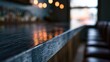 © Ade - Dark wood bar counter reflection, soft light, blurred seats, cozy evening ambiance