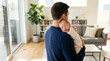© imagemir - A tender moment as a Caucasian father holds his sleeping newborn in a cozy living room, showcasing love and connection.