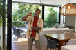 © wavebreak3 - African American man standing in modern home near sliding doors holding tablet and gesturing