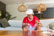 © wavebreak3 - Man wearing white VR headset holding controller, laughing and leaning on sofa at home, red shirt