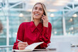 © Westend61 - Smiling young businesswoman with notebook on the phone