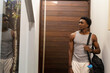 © wavebreak3 - African American man standing in entryway wearing grey tank top, carrying black gym bag, copy space