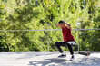 © wavebreak3 - Man performing squats hands-behind-head on deck by railing, red shirt, mat and bottle, copy space