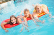 © Tatyana Gladskih - Woman and kids playing on inflatable rings in blue swimming pool water. Happy family having fun during summer vacation. Active lifestyle and recreation concept with joy and leisure.
