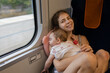 © Anna - 6-month-old baby sleeps sweetly in his mother's arms during a train ride. Summer trip. Inconveniences when traveling with a small child. Going on vacation or returning home.