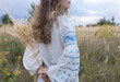 © Anna - beautiful adult girl with loose hair wearing a traditional embroidered blouse in nature. Support Ukraine. The younger generation of Ukrainians. National identity. Selective focus on embroidery