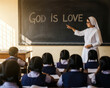 © Shootdiem - Religious teacher pointing at chalkboard message while students listen