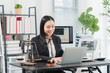 © Kritdanai - Lawyer Working at Desk: A professional female lawyer diligently works on her laptop at a well-organized desk, surrounded by legal books, a scale of justice, and a gavel.
