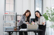 © Kritdanai - Collaborative Legal Minds: Two professional women, possibly lawyers or paralegals, deeply engaged in discussion over a laptop in a modern office setting.