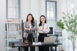 © Kritdanai - Professional Portrait: Two confident female lawyers stand in a well-appointed office, a symbol of justice on the desk and a bookshelf filled with legal texts, exuding competence and legal expertise.
