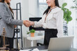 © Kritdanai - Professional Handshake: Two businesswomen shake hands, symbolizing a successful agreement and partnership in a modern office setting, with legal scales visible in the foreground.