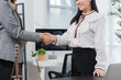 © Kritdanai - Partnership Affirmation: Two businesswomen share a firm handshake, symbolizing a successful agreement and a strong alliance within a professional office environment.
