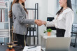 © Kritdanai - Legal Agreement Handshake: Two professional women, a lawyer and her client, shake hands in agreement within a well-appointed office setting, symbolizing trust and a successful legal conclusion.