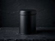 © anca - Sleek matte black metal tin container on a dark textured slate surface, perfect for minimalist packaging or product display