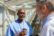 © Marko Geber - Healthcare workers talking during coffee break in hospital corridor