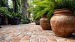 © nur - Large weathered clay containers holding lush green foliage line a rustic brick pathway in a garden setting.