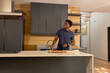 © wavebreak3 - African American man assembling pizza on cutting board at marble kitchen island, copy space