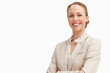 © wavebreak3 - Female exec standing arms crossed, smiling in studio, wearing beige blazer white blouse, copy space