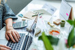 © Rawpixel.com - Person typing on a laptop at a cluttered desk with tea and papers.