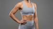 © ณภัทร วงค์มาวิวัฒน์ - Sculpted Strength: A woman's toned physique, showcasing defined abdominal muscles and athletic build, stands confidently in a grey sports bra and leggings.