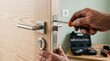 © Image - A person installing a modern door lock with a screwdriver in a home interior setting