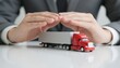 © ANDREY PROFOTO - Truck protection and logistics insurance concept with businessman's hands over toy semi-truck
