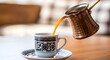© MistoGraphy - Traditional Turkish coffee being poured from a cezve into a decorative ceramic cup and saucer, showcasing a rich cultural beverage ritual with warm tones.