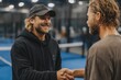 © Alexei - Two male tennis players shake hands after a match on a blue indoor court, wearing casual sports attire with a net and spectators visible in the background