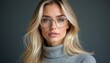 © Pete - Blonde woman with clear frame glasses, wearing grey turtleneck. She looks directly at camera. Pro and modern look. Fashionable eyewear accessory.