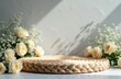 © Pete - Woven round platform with cream roses and baby breath flowers. Natural organic display base for product presentation against textured wall with shadow patterns.
