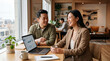 © DH Tree Stock - Two business professionals collaborating and reviewing data on a laptop during a meeting in a modern, bright office space with a view of the city skyline.