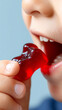 © dinatychynska - Child eating red gummy bear candy, closeup mouth teeth. Kid consuming jelly sweet treat, dental health concern. Sugar snack, cavity risk, tooth decay, nutrition concept.
