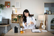 © Stella 16 - Smiling Asian female physician examines a skeletal foot model at her desk, ideal for healthcare, orthopedics, and medical education content