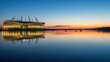 © rohmat - Modern sports stadium reflected in calm water at sunset.