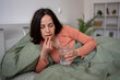 © Jelena - Woman taking medicine for illness and health recovery in bed