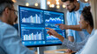 © Nataliya - Corporate team gathered around a large monitor displaying analytics data during a strategy session, data-driven leadership and group decision making concept, faceless, defocused