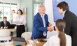 © JackF - Elderly male bank manager shakes hand with young couple customers during business meeting