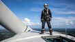 © True Stock - Engineer standing on top of a wind turbine overlooking the landscape.