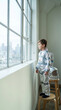 © Yauhen - Little boy wearing homemade foil astronaut suit looks out window. Father watches smiling. Concept of childhood imagination and dreams. Ideal for family and education themes.